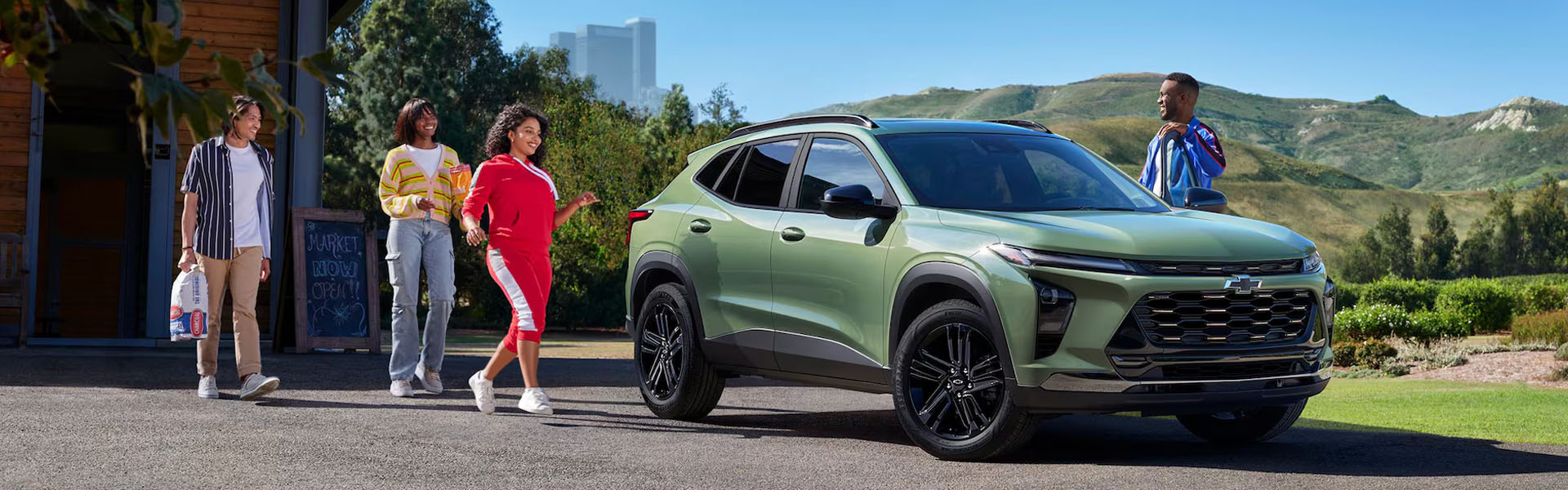 2026 Chevy Trax ACTIV compact SUV parked outside a market in a scenic mountain setting.